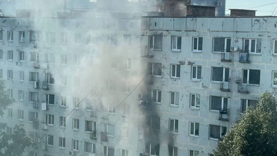 Панельна багатоповерхівка з густим димом біля вікон і фасаду